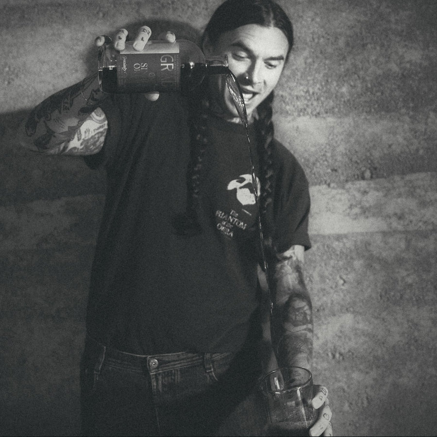 Pouring GRADA from the bottle into a glass over ice, in black and white