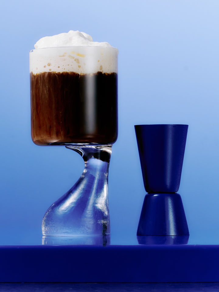A GRADA Irish coffee in a stemmed glass under a float of whipped coconut cream